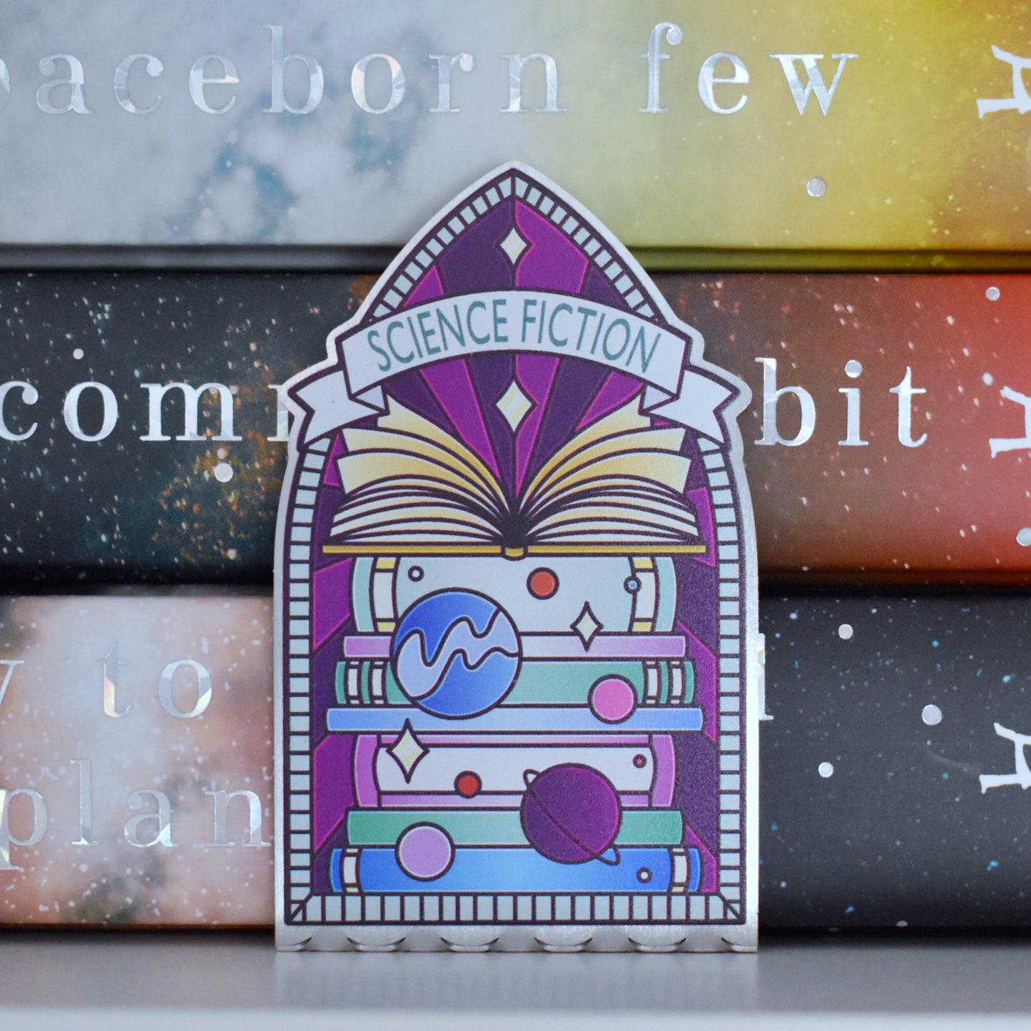Decorative stainless steel standee with 'Science Fiction' design on in the style of a stained glass window pushed up against a stack of books.