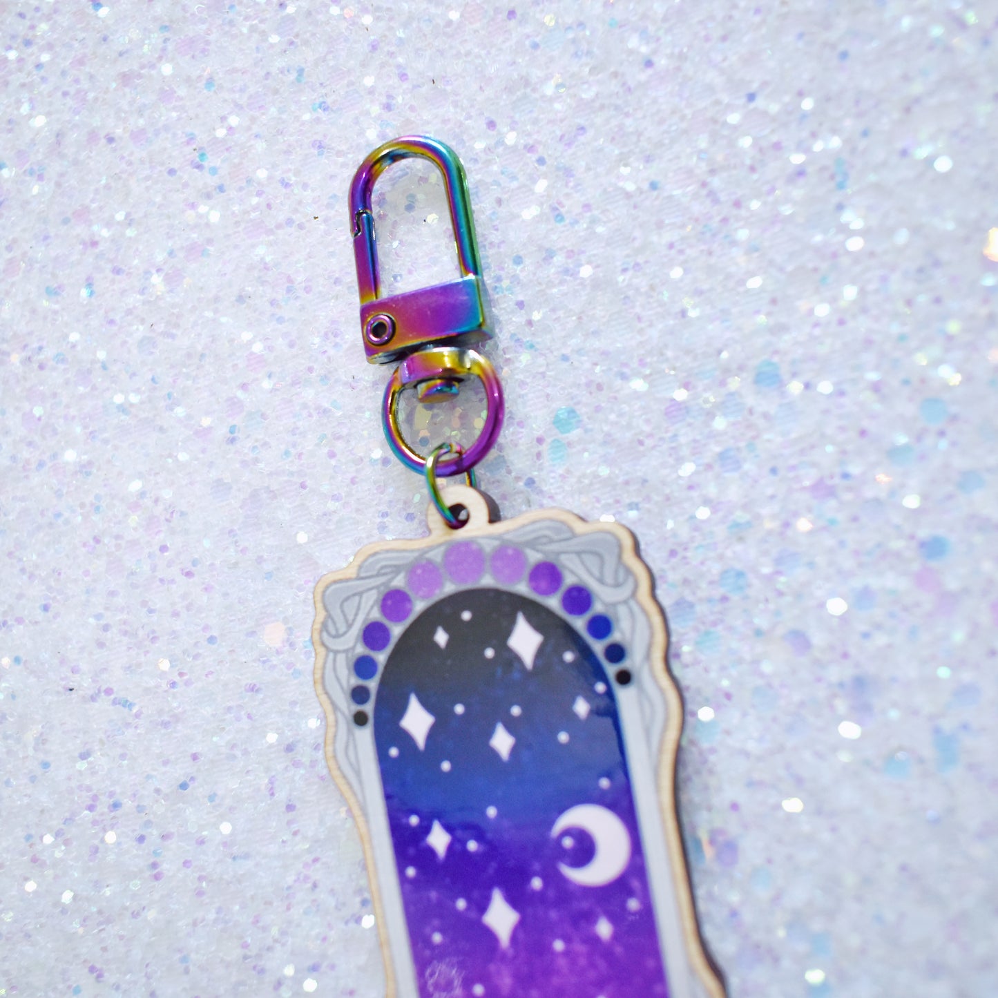 Close up of rainbow metal keychain attachment with lopster style clasp, attached to the top of wooden charm.
