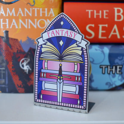 Decorative stainless steel standee with 'Fantasy' design on in the style of a stained glass window with a stack of books behind.