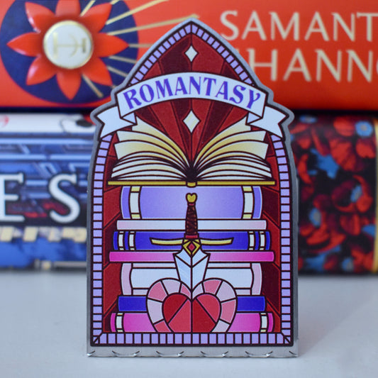 Decorative stainless steel standee with 'Romantasy' design on in the style of a stained glass window with a stack of books behind.
