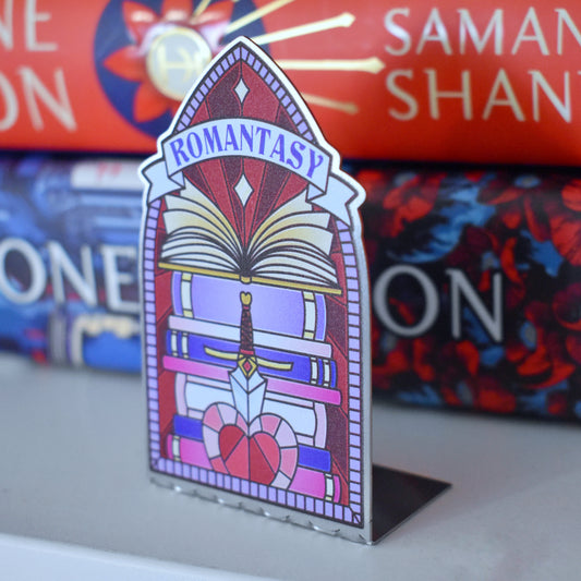Decorative stainless steel standee with 'Romantasy' design on in the style of a stained glass window at an angle to see it is an L shape with a stack of books behind.