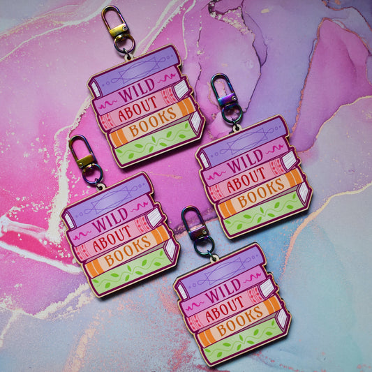 Four wooden keyrings in a slanted diamond shape, with a colourful book stack design with detailed spines and 'Wild About Books' text. On a colourful watercolour style background.